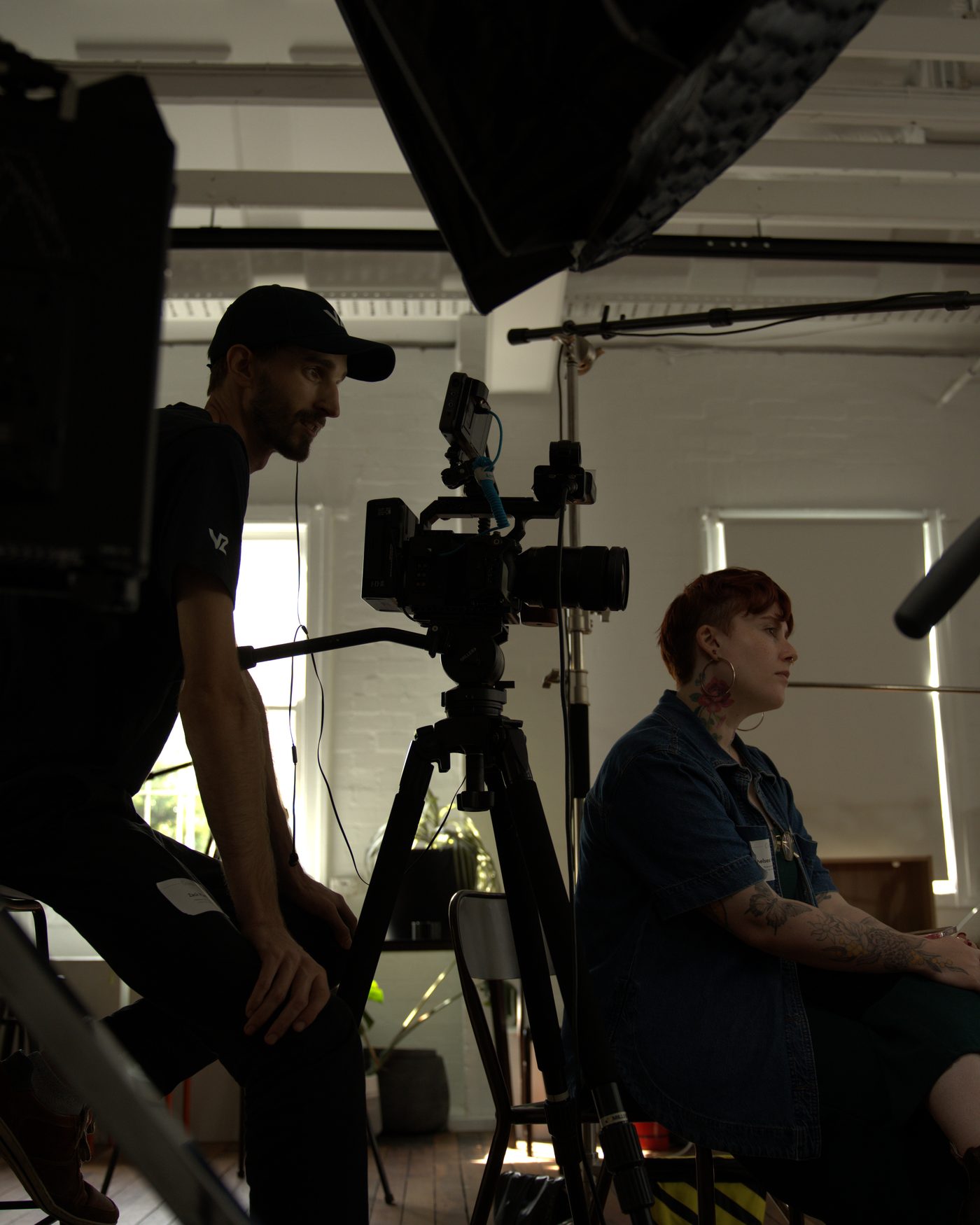 On set between takes: the producer perched on a stool beside the camera, talking with the person in the chair.