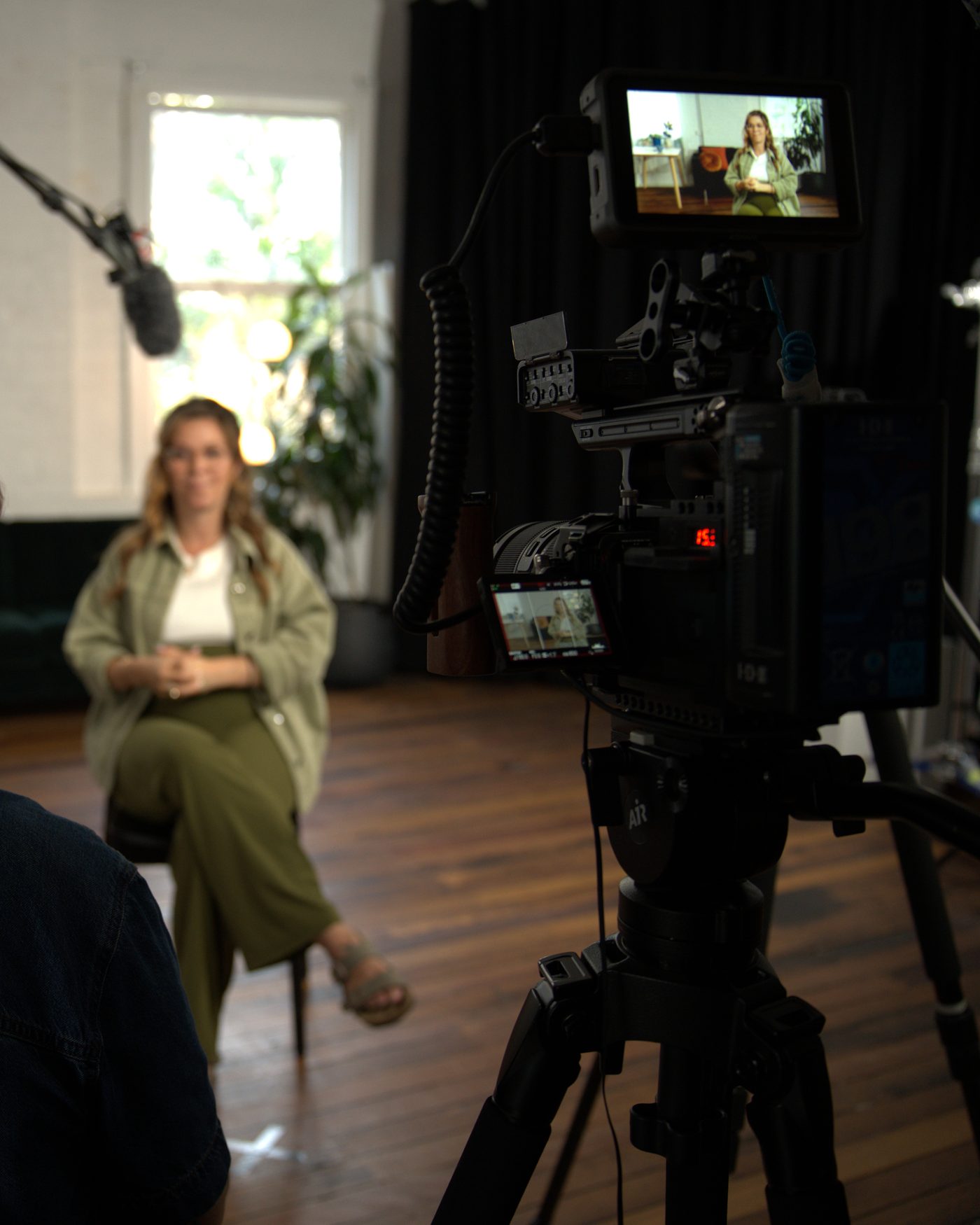 The camera monitor holding the composed interview shot, the set arranged around it.