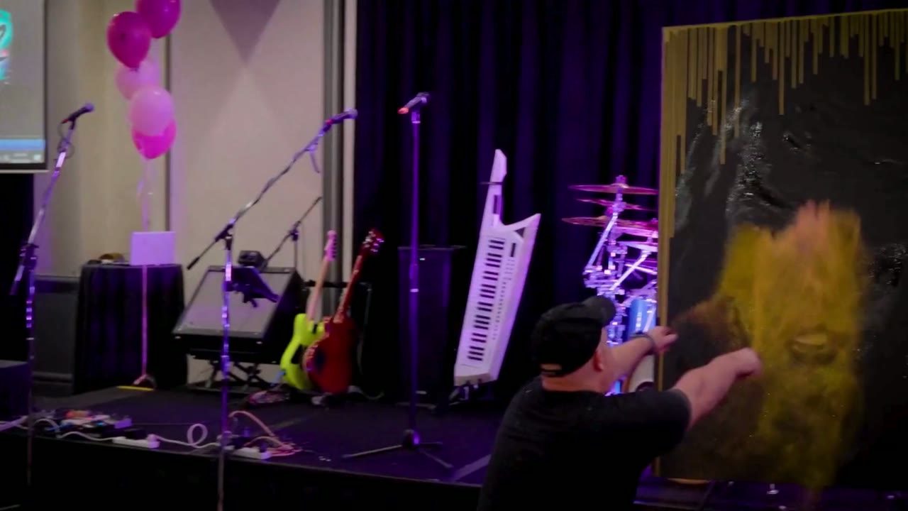 A live painting on stage at an event, a band&rsquo;s instruments set up behind