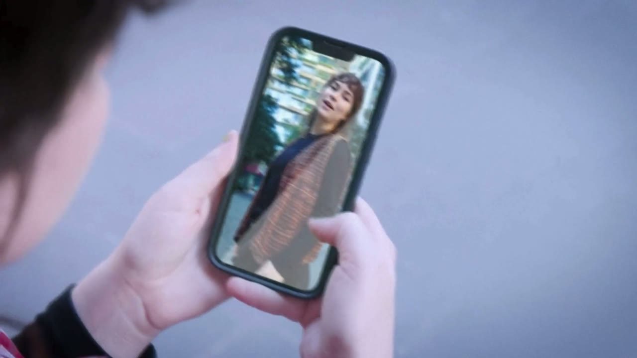 Hands holding a phone playing a video